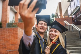 Glad young university students celebrating their graduation day, posing for a selfie while proudly
