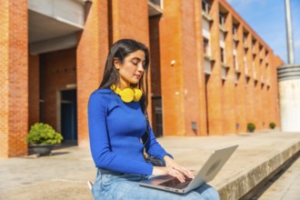 Young woman in casual clothing engaging in remote learning or project work on a laptop, sitting