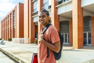 Young hispanic man student standing outdoors at university campus, wearing a backpack and holding