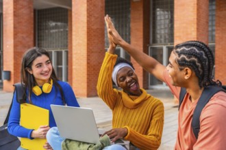 Diverse group of university students on campus sharing a triumphant high five, smiling and