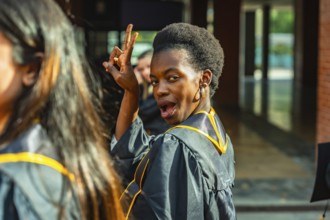 Young black woman in a graduation gown celebrating academic achievement, looking back at the camera