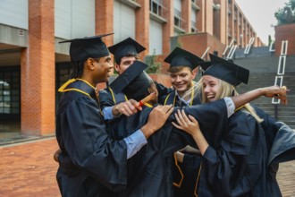 Group of diverse university students wearing academic dress and caps, standing outside a campus