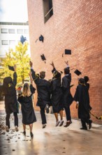 Diverse group of university students celebrating an achievement and success by throwing graduation