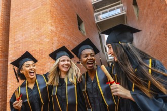 Diverse group of happy female students celebrating their university graduation, proudly wearing