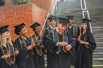Diverse group of smiling university graduates in caps and gowns celebrating educational success and