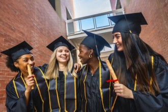 Diverse group of female university graduates standing together outdoors, smiling and laughing while