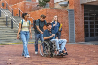 Group of diverse university students walking on a brick pathway, one student using a wheelchair