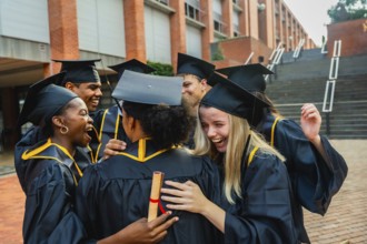Graduated students are embracing each other and laughing, celebrating their academic achievement