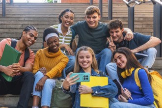 Diverse group of happy university students smiling and posing together on campus stairs, taking a