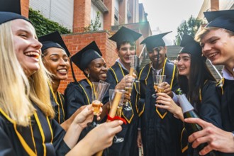 Group of smiling diverse students celebrating university graduation, wearing academic dress,