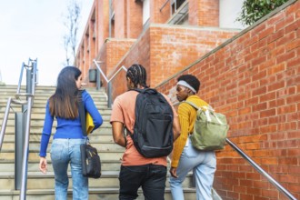 Group of diverse university students with backpacks and books walking up outdoor stairs,