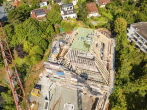 Roof of a house under construction with crane and surrounding houses in the countryside,