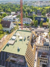 Top view of a building with a crane in an urban environment with lots of greenery, carpentry