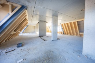Unfinished interior with concrete pillars and wood paneling, light penetrating, carpentry