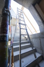 A steel staircase leads to a ladder under a concrete opening that leads upwards, carpentry
