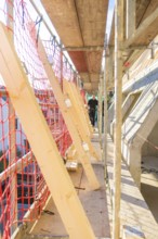 Close area of scaffolding with red safety nets and wooden struts, carpentry construction, roof