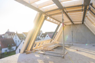 An unfinished roof truss with a view of a settlement at sunrise, construction of a carpentry