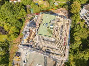 Bird's eye view of a building with roof structure, surrounded by green landscape, carpentry