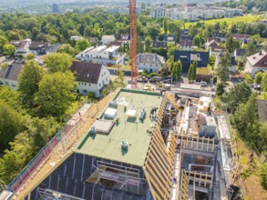 Panoramic view of a building under construction with crane and green surroundings, carpentry