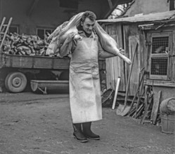 Slaughter day on a farm, farmer carrying a pig's leg on his shoulder, black and white, Middle