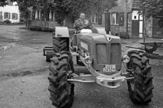 Farmer on his new Schlüter tractor in the yard, black and white, Tauchersreuth, Middle Franconia,