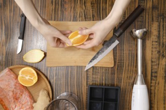 Hands peel an orange over a cutting board. Knives, a blender, and other items surround. The kitchen