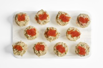 Twelve beautifully crafted tuna tartlets sit on a white platter. Each tartlet is filled with a