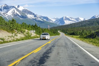 Car on road through taiga and mountainous landscape, picturesque landscape on Richardson Highway,