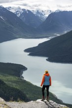 Female mountaineer enjoying views of blue lake and mountains on Twin Peaks Trail, Eklutna Lake,