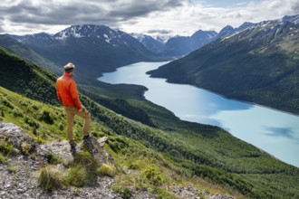 Mountaineer enjoys views of blue lake and mountains on Twin Peaks Trail, Eklutna Lake, Chugach