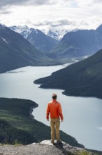 Mountaineer enjoys views of blue lake and mountains on Twin Peaks Trail, Eklutna Lake, Chugach