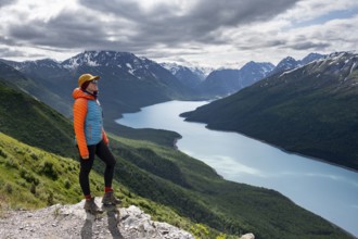 Female mountaineer enjoying views of blue lake and mountains on Twin Peaks Trail, Eklutna Lake,