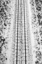 A railroad track in winter surrounded by snow, black and white photography Germany