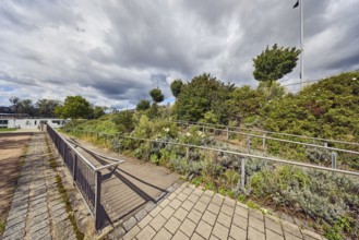 Access to Europe Bridge, park, wooden ramp, stainless steel railing, trees, flower bed, plants,