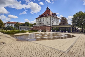 Villa Schmidt restaurant, park, fountain, hedge, lawn, paths, trees, blue partly cloudy sky,