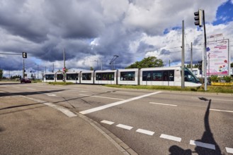Tram, street, sidewalk, lanes, overhead line, central island, trees, meadow, rainy mood, blue sky,