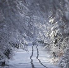 Car driving in lane across heavily snow-covered road with heavy amounts of snow through a winter