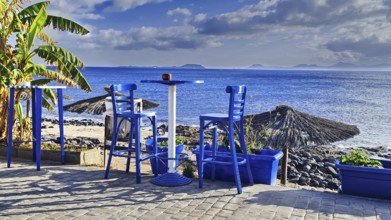View of the sea from a terrace with blue chairs. A relaxed, sunny coastal scene, Playa Blanca