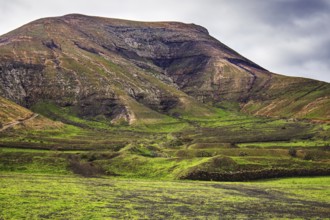 Green hills and mountain landscape under a cloudy sky, Yaiza Lanzarote