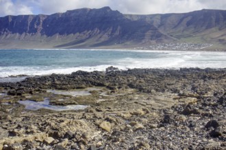 Rough coastal landscape with rocks in the foreground and mountains in the background (Risco de