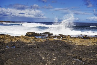 Dramatic scene of waves hitting black rocks on a sunny day, Playa de Caleta de Famara, Teguise