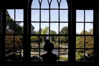 View through a window of a well-kept garden with a bust in the foreground, zero