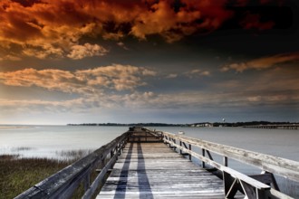 Long pier under a dramatically colored evening sky with clouds, Hunting Island, South Carolina, USA