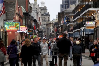 Bustling Bourbon Street at night with numerous passers-by and illuminated signs, New Orleans,