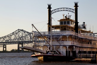 Paddle steamer on the river in front of a bridge in warm sunlight, New Orleans, Louisiana, USA