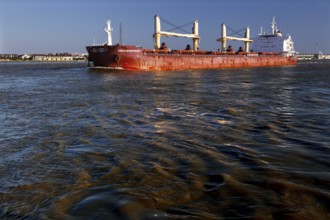 Cargo ship on a river with reflecting water and blue sky, New Orleans, Louisiana, USA