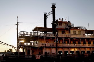 A paddle steamer on the River Front, illuminated at dusk in New Orleans, New Orleans, Louisiana,