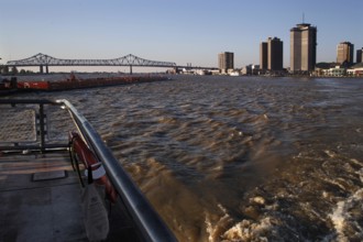 View of Mississippi River with skyscrapers and bridge at sunset, New Orleans, Louisiana, USA