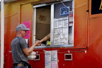 Person orders food from a colorful food truck full of menu boards, Natchez, Mississippi, USA