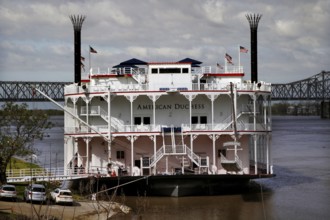 Historic paddle steamer docked on the riverbank, a bridge in the background, Natchez, Mississippi,